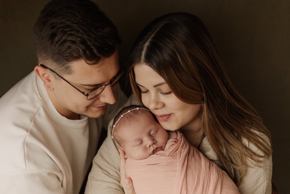 Newbornshooting Ansbach – Eltern halten ihr schlafendes Baby liebevoll im Arm, natürliche Neugeborenenfotografie