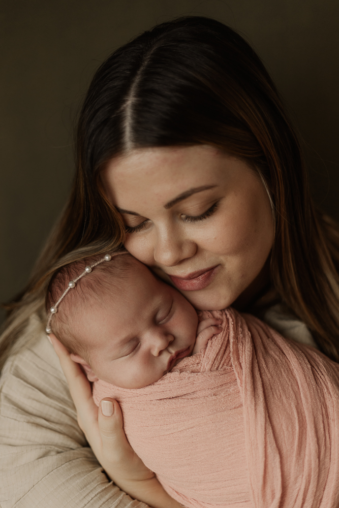 Neugeborenenfotografie Ansbach – Mutter hält ihr schlafendes Baby liebevoll im Arm, natürliche Newbornfotografie