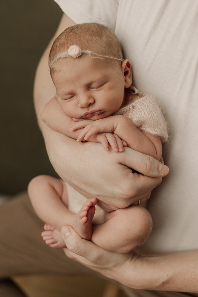 Neugeborenenfotografie Ansbach – schlafendes Baby wird liebevoll im Arm gehalten, natürliches Newbornshooting zuhause