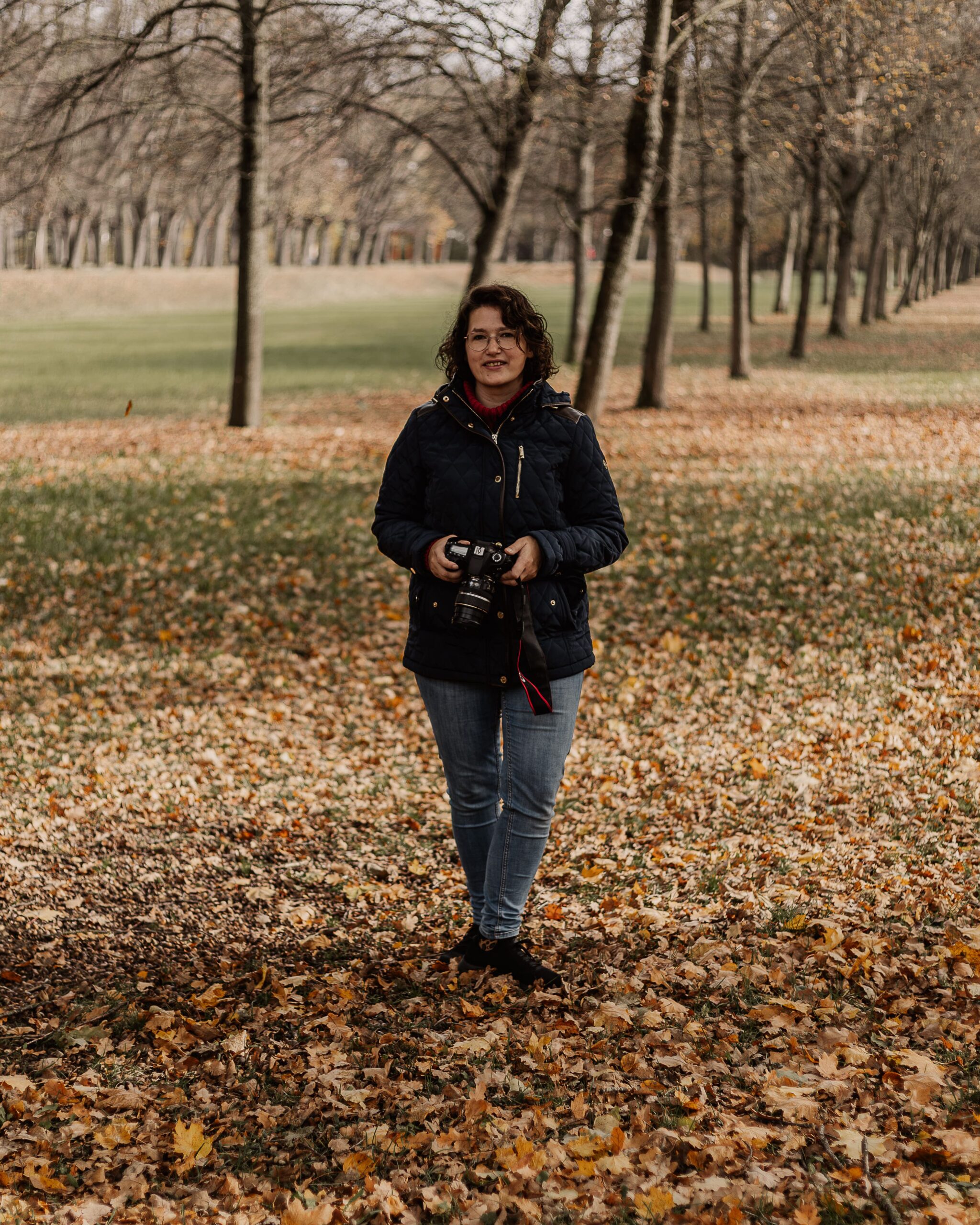 Sandra von Matelis Fotografie steht mit Kamera im herbstlichen Park im Landkreis Ansbach – Familienfotografin für natürliche Familienmomente