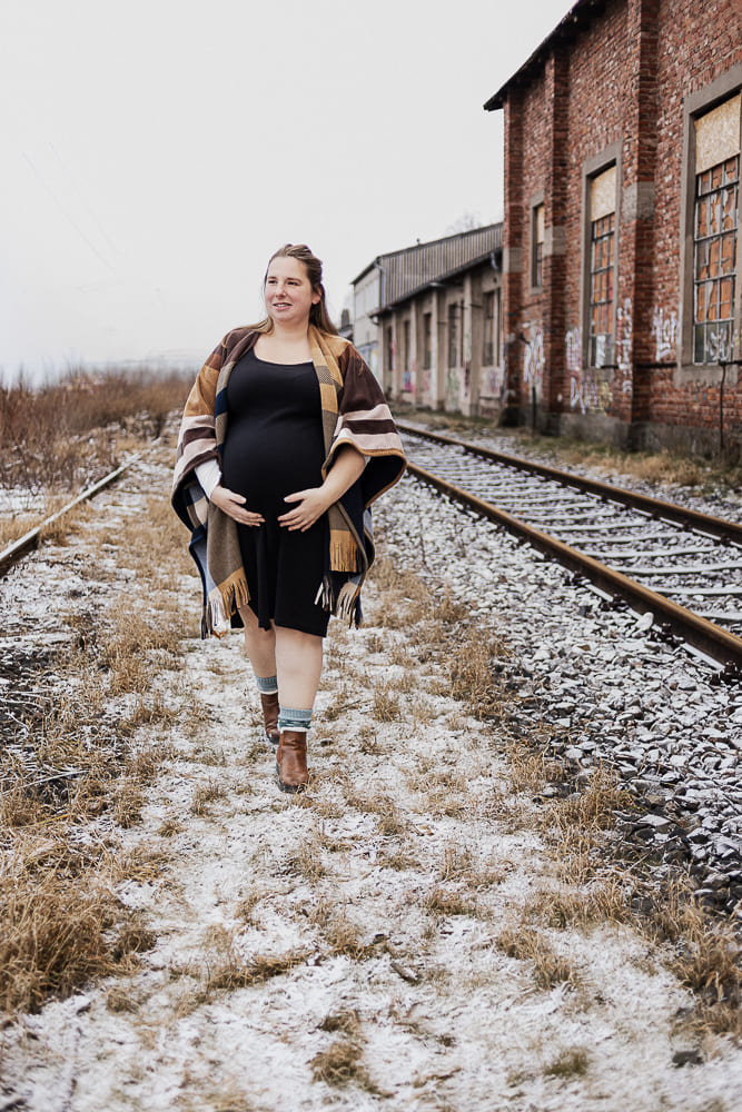 Babybauch Fotoshooting bei Ansbach – schwangere Frau läuft entlang von Gleisen in natürlicher Umgebung