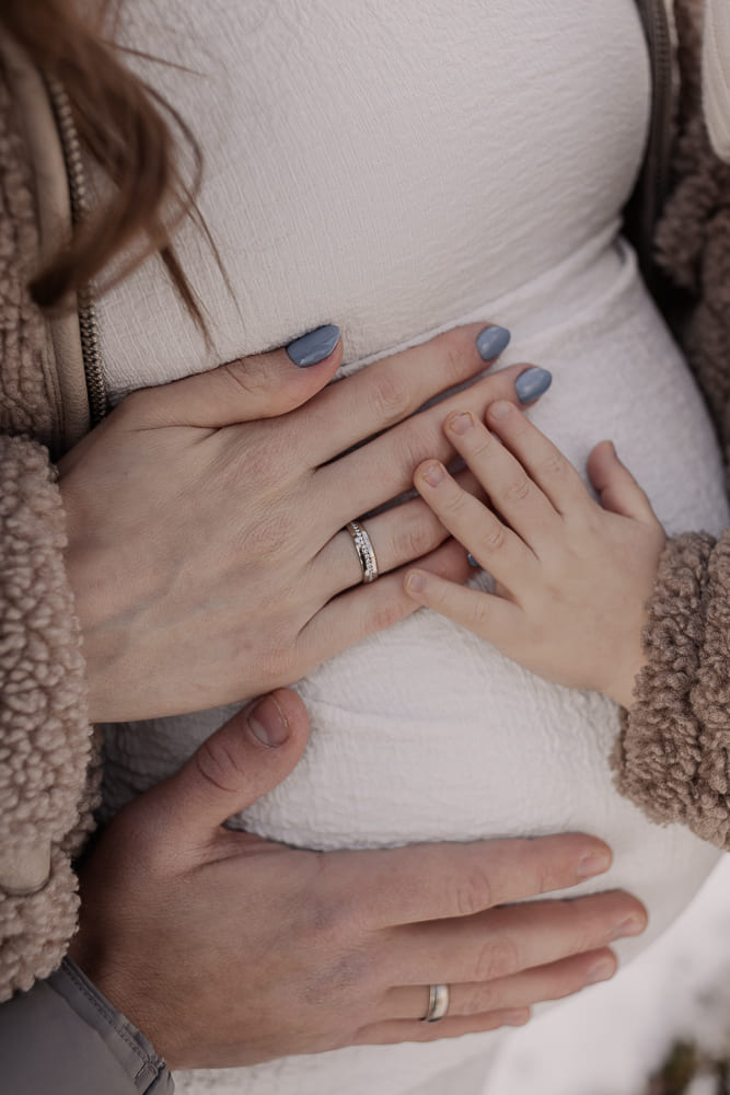 Babybauch Fotoshooting – Hände von Eltern und Kind auf dem Bauch in natürlicher Familienfotografie
