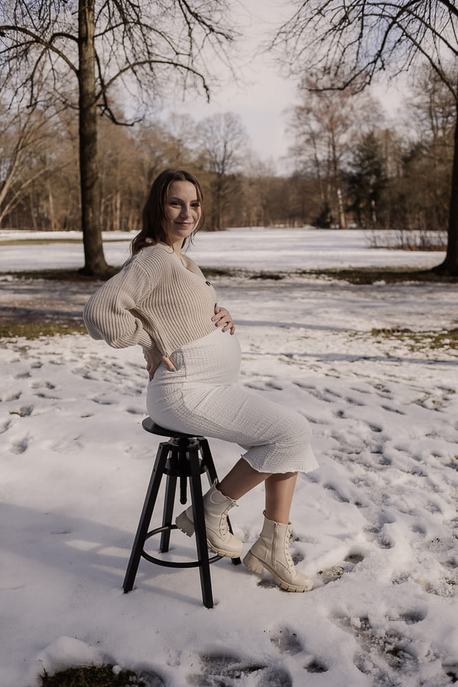 Babybauch Fotoshooting im Freien bei Ansbach – schwangere Frau sitzt entspannt im Schnee