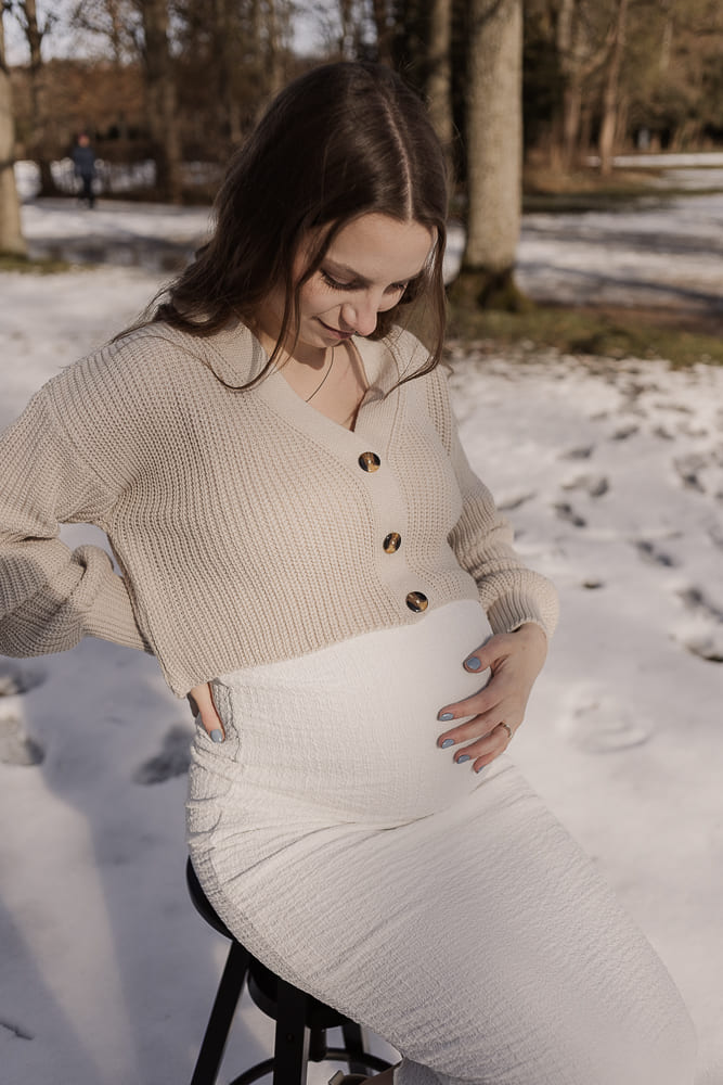Babybauch Fotoshooting im Freien bei Ansbach – schwangere Frau hält liebevoll ihren Bauch im Schnee