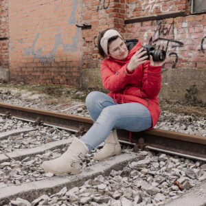 Fotografin aus Ansbach sitzt auf Bahnschienen und überprüft ihre Kamera während eines Shootings