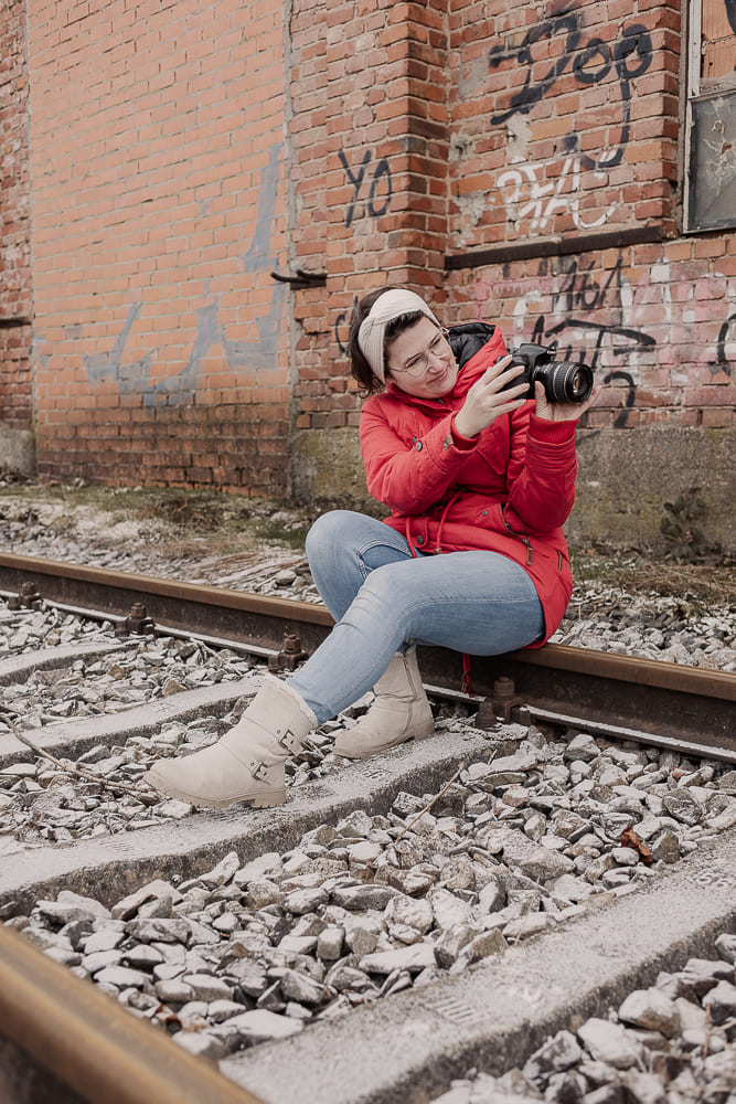 Fotografin aus Ansbach sitzt auf Bahnschienen und überprüft ihre Kamera während eines Shootings